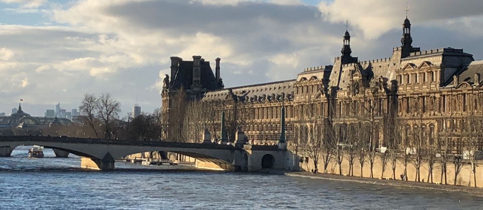 Photo of Paris with Sena river and Louvre museum in the background during sunset
