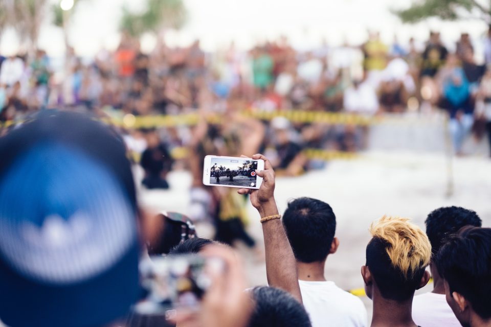 Hand holding a smartphone and taking a picture of a protest in the background