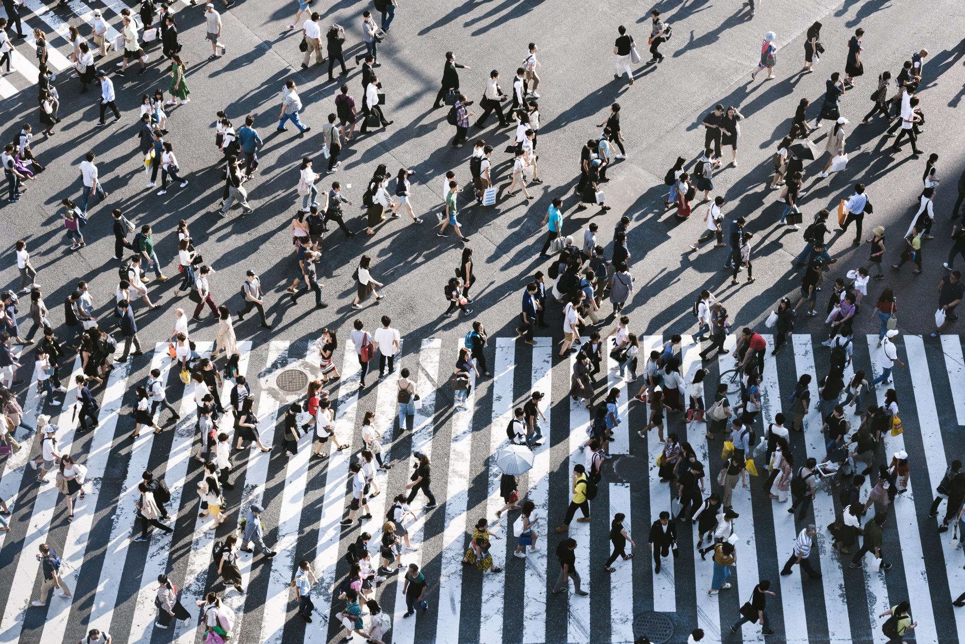 A crowd crossing a road during the day seen from above