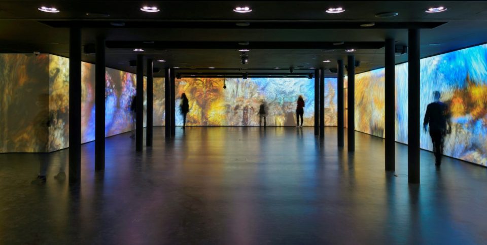 Photo of people walking around an immersive projection exposition