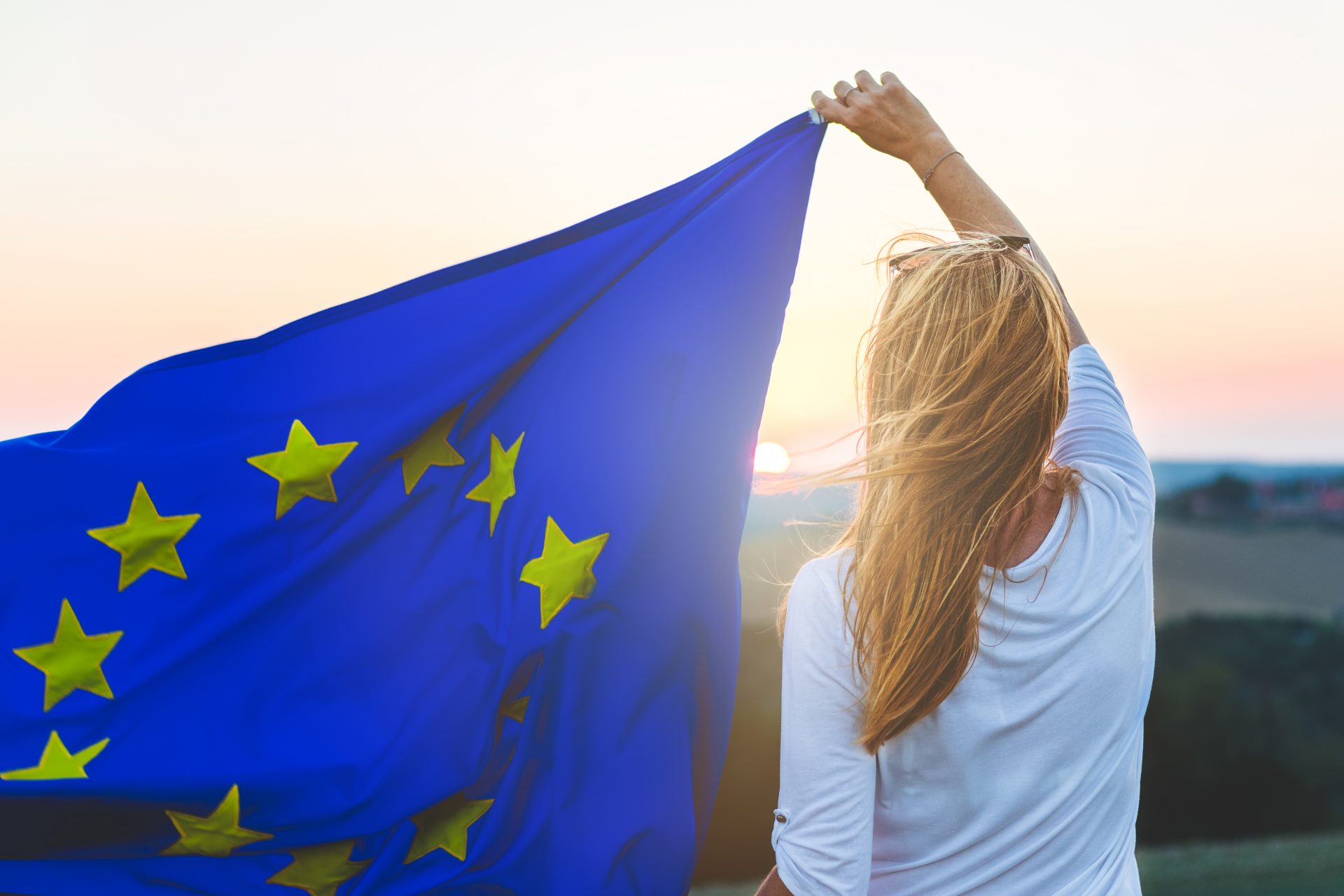 Woman holding an European flag with the sunset in the background