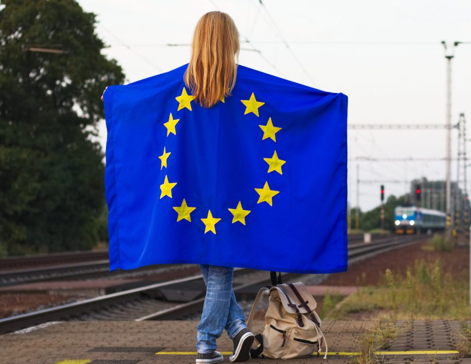 Traveling through the European Union by train. Backpacker with European flag