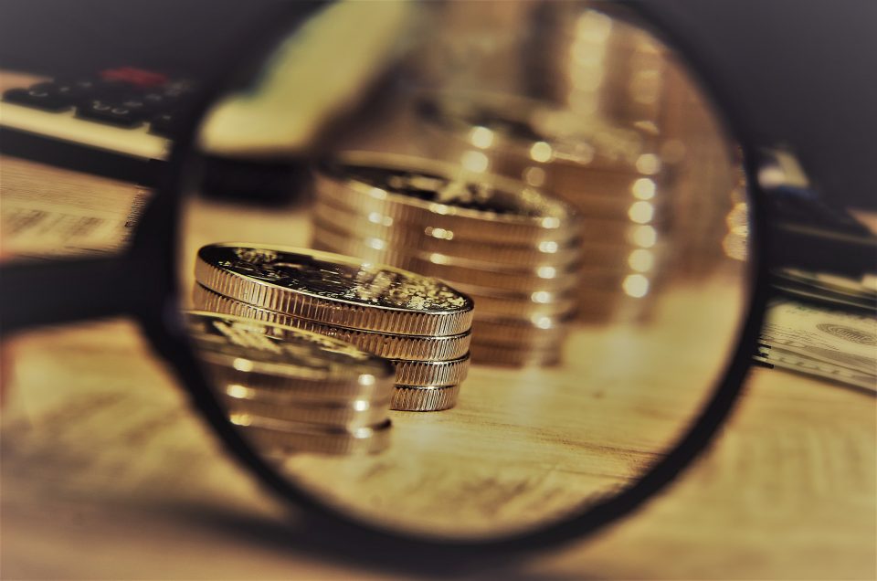 Stacks of Coins in Order of Growth Visible Through a magnifying glass