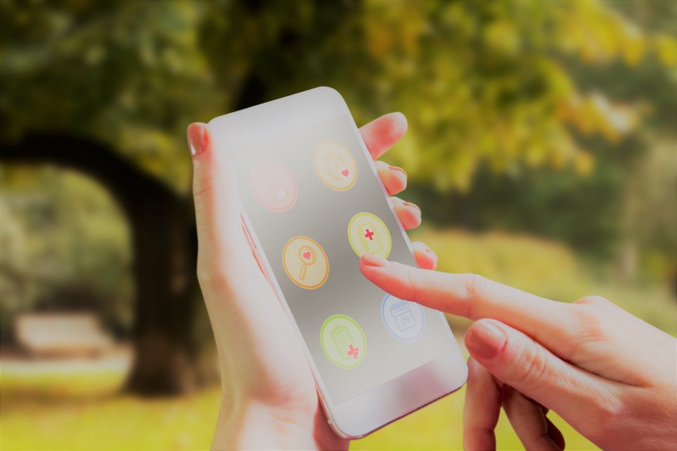 Hand holding futuristic Smartphone Against Trees and Meadow in the Park