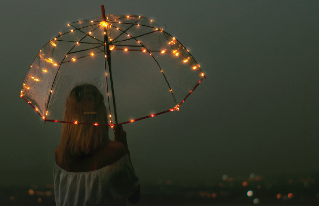 Girl holding up an umbrella with lights with a foggy landscape in the background