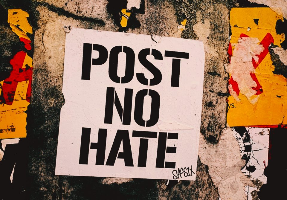 White poster with the message "Post no Hate" in black letters stamped on a wall