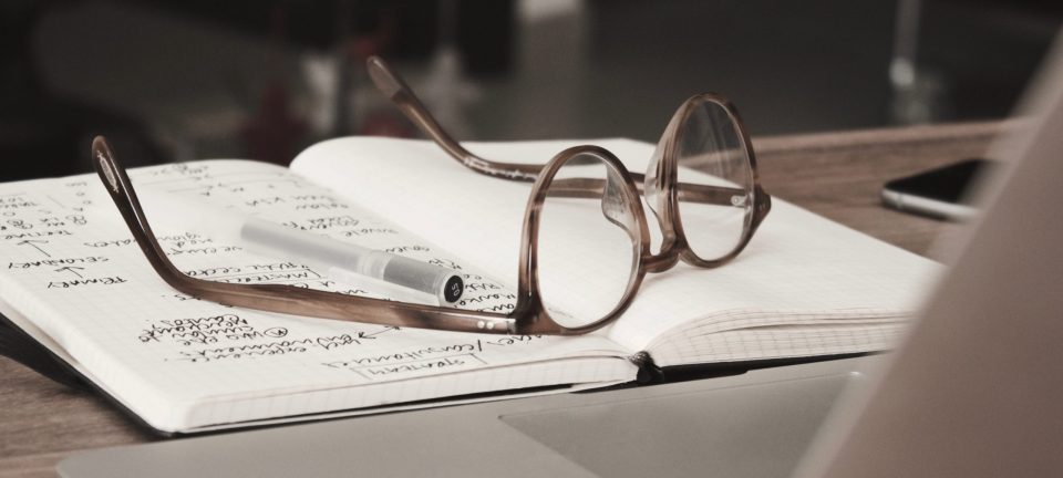 Conceptual picture with a pair of glasses on a notebook in front of a computer